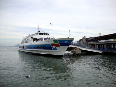 Ferry docked at the San Francisco waterfront with view of the Bay Bridge on a calm day