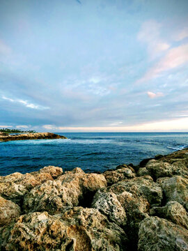 Sunset over the tranquil waters of Ko Olina, Oahu, revealing rocky formations and a serene coastline