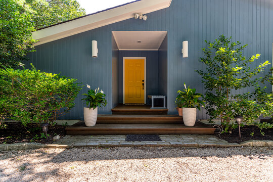 Modern house entrance with blue exterior siding and yellow front door