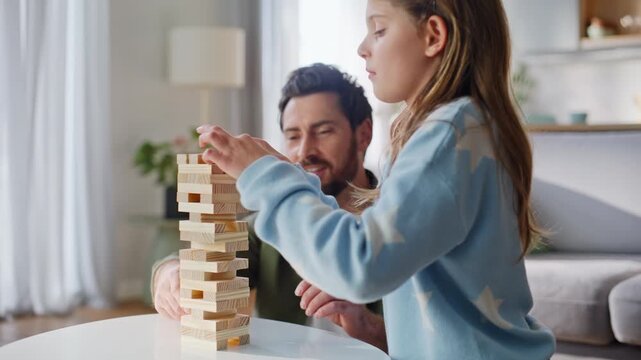 Father daughter playing jenga living room closeup. Smiling man building tower