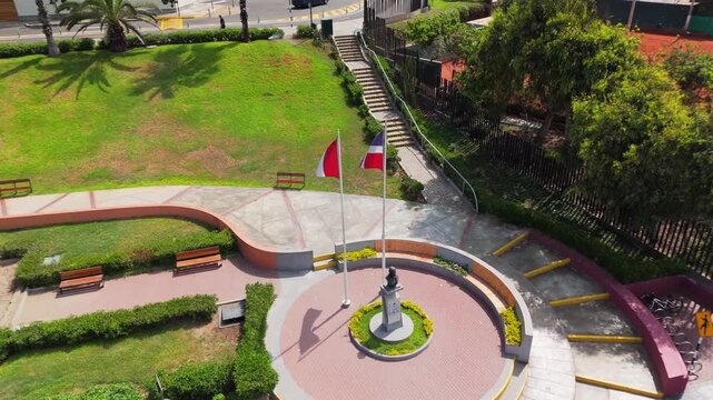 Aerial view of a serene park in Lima, Peru, featuring a statue and the Peruvian flag