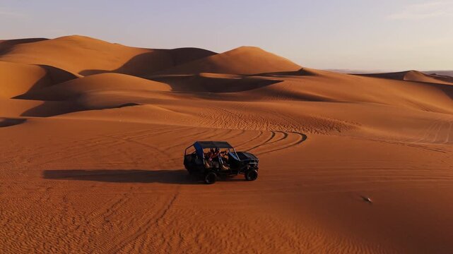 Dune buggy traversing Peru's expansive sand dunes at sunset
