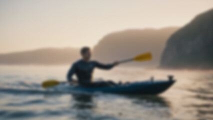Naklejka premium Blurred background of muscular man in a navy wetsuit rows vigorously on the open ocean at sunrise, water glistening on his arms as small waves break around the kayak. Golden-pink light reflects.