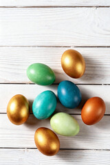 A basket of colorfull Eastereggs, on a white wooden background.