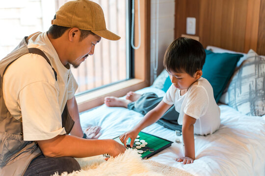 Father and son playing Othello in the bedroom