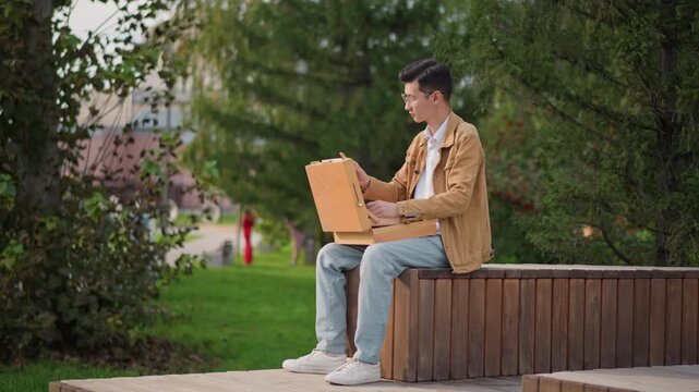 white male artist painting outdoors, vibrant park bench scene with trees and urban backdrop freelance illustrator and content creator testing color studies on portable board, playful strokes, smiling