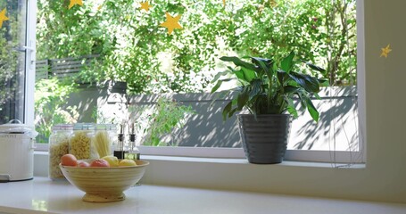 Fototapeta premium Displaying ribbed grey pot with plant on windowsill at kitchen counter, with fruit bowl, copy space