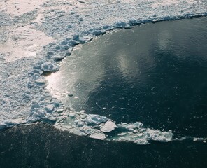 Aerial View of Turquoise Ocean Water with Ice Floes Sparkling in Sunlight on Cold Climate Landscape
