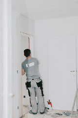 A vertical portrait of a mature construction worker plastering a doorway.