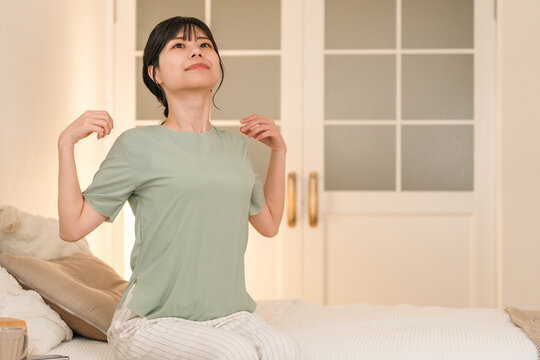 Young Asian woman suffering from stiff shoulders in her bedroom at night
