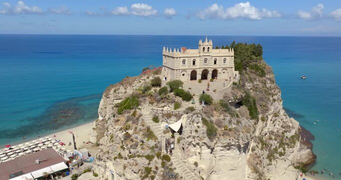 Panorama of the Church of Santa Maria dell'Isola, located in Tropea, Calabria, southern Italy. Aerial view of a Catholic sanctuary perched on a cliff overlooking the crystal-clear turquoise sea.