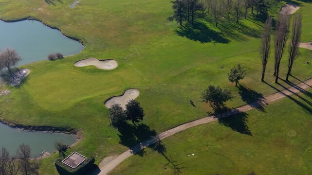 Lone golfer walking on a sunny golf course path