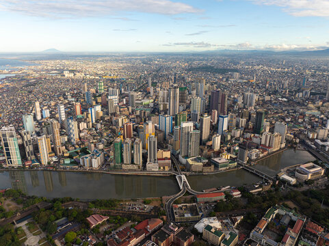 Aerial view of Manila, Philippines, showcasing modern skyscrapers and crowded residential areas reflecting in Pasig River, creating an iconic cityscape of an Asian metropolis