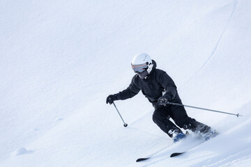 新雪のゲレンデにシュプールを描くスキーヤー