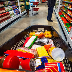 Point-of-view shot from inside a full grocery cart in a supermarket aisle © poco_bw