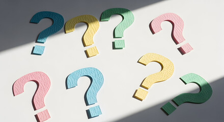 Colorful question marks on white background with dramatic lighting