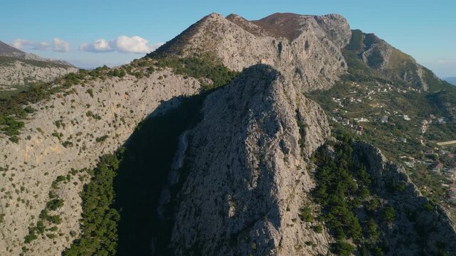 Epic aerial view of Mirabella Fortress tower on a steep cliff above Omis Old Town, Cetina river canyon and Adriatic sea, Croatia, 4K