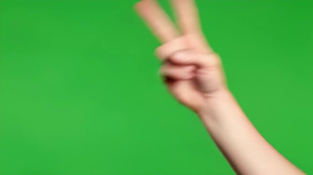 A hand is making the peace sign with two fingers on a green background