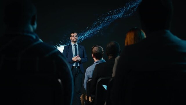 CEO speaker engages with the audience during business meeting presentation in conference hall, taking the stage and starting discussion at panel. Audience of attendees at networking event. Camera A.
