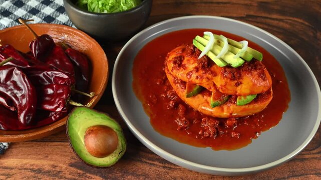 Traditional Mexican drowned sandwich also known as Mexican pambazo or chancla poblana, with red adobo sauce, avocado, and sliced ​​onions, aerial view