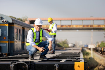 Transportation engineers inspecting train, Rail industry professionals monitoring rail operations at maintenance site, Railway supervisors coordinating operation with radio communication at train yard