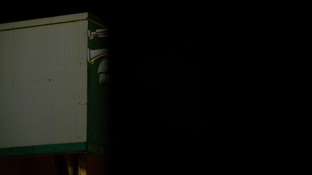 Multiple CCTV cameras mounted on building corner at night, revealed by sliding camera move from behind dark, out-of-focus foreground. Cinematic surveillance, observation, urban security concept. Clip2