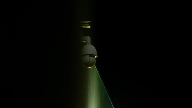 Multiple CCTV cameras mounted on building corner at night, revealed by sliding camera move from behind dark, out-of-focus foreground. Cinematic surveillance, observation, urban security concept. Clip1