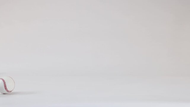 Three White Baseballs Bouncing Across a Plain White Studio Background