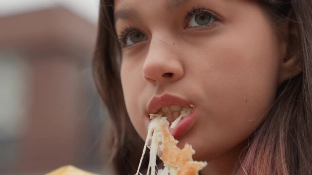 closeup student tasting pastry rooftop, profile shots with distant skyline, cool wind ruffling hair, slow chew, glaze stringing from bite, solemn gaze into distance, campus break mood