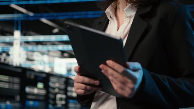 Close up of programmer walking in data center, optimizing server load balancing using tablet. Server room IT expert adjusting system parameters on device application to improve efficiency, camera A
