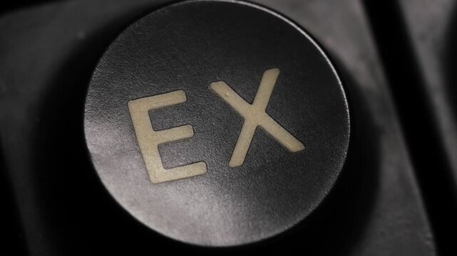 Close up of a finger pressing an EX button on a keypad in low light, macro close up