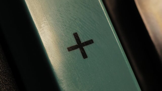 Close up of a finger pressing a green plus button in low light