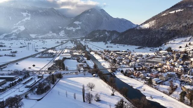 Winter view of Weesen, Switzerland. Snowy rooftops and a quiet harbor nestle against the deep blue Walensee, surrounded by the majestic peaks of the Glarus Alps.