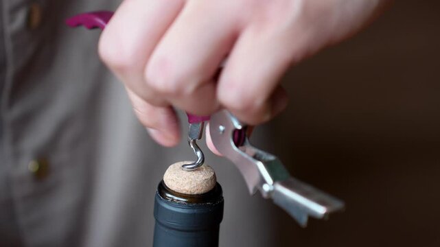 Detailed close-up of a corkscrew opening a wine bottle. Slow motion action highlights ritual, anticipation and craftsmanship associated with wine culture and dining experience.