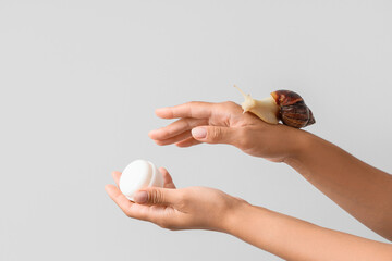Female hands with snail and jar of cream on grey background © Pixel-Shot