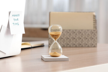 Hourglass and sticky notes on table in office
