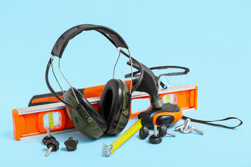 Fototapeta premium Carpenter's tools and hearing protection earmuffs on blue background