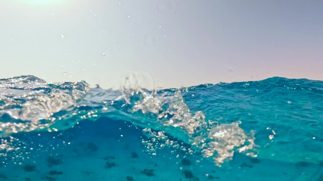 Half underwater slow motion view of sea waves with distant anchored small motor boat