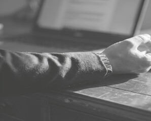 Close Up of a Hand Resting on a Table Near a Laptop in a Black and White Workspace Setting