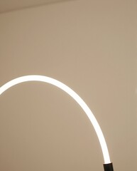 Curved Bright Light Fixture Casting Soft Shadows in Minimalist Interior Space