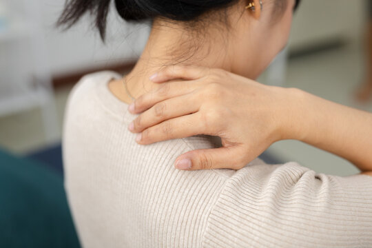 Close up of women touching neck and shoulder with pain at home. Muscle tension, neck strain, stress, fatigue, office syndrome, unhealthy posture, daily lifestyle discomfort concept.