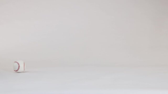 White Baseballs Bouncing and Rolling Across a Plain White Background