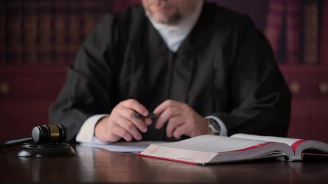 Judge pointing the pen, signing the document and strikes wooden gavel on desk after listening while Statue of Justice stands on desk. courtroom authority, legal decisions,