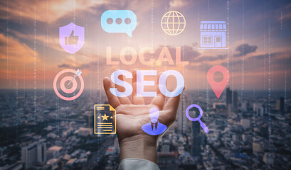 Naklejka premium A hand extends towards translucent icons representing local SEO concepts over a city skyline at sunset, illustrating the fusion of digital marketing with urban landscapes. Gantry