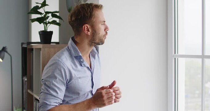 Man battling stress and anxiety considers problem. In a quiet office, he gazes through the window, weighing burnout, frustration, and mental health pressures. Clear concept of anxiety at work.