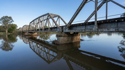 Fototapeta premium A serene bridge spans across a calm river under a clear blue sky in a wide shot view