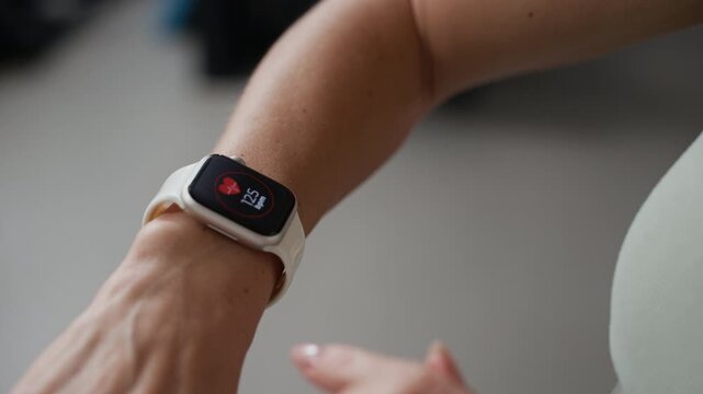 Close up shot of unrecognizable sportswoman checking smartwatch fitness data and heart rate during indoor training