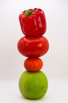 Mandarin, apple, tomato and sweet pepper in the form of a tower on a white background, the concept of healthy eating from fruits and vegetables, health care, fruit diet, vegans and vegetables. High qu