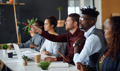 Obraz premium Meeting, pointing or people with feedback in office, creative workshop or idea for planning challenge. Brainstorming, laptop or team discussion for decision making, strategy proposal or suggestion