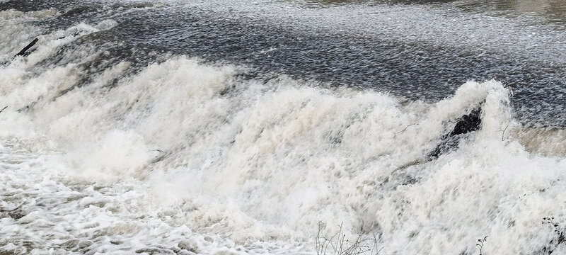 Primer plano de agua brava cayendo con fuerza y formando espuma blanca en un salto de r&iacute;o